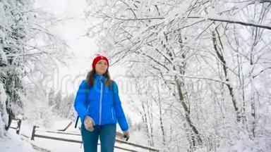女人沿着一条小路走在美丽的冬天白雪覆盖的风景中。 晴朗的晴朗的霜冻天气。 慢动作